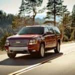 A red 2014 Chevy Suburban is shown driving near a lake after researching an Indianapolis online car dealer.