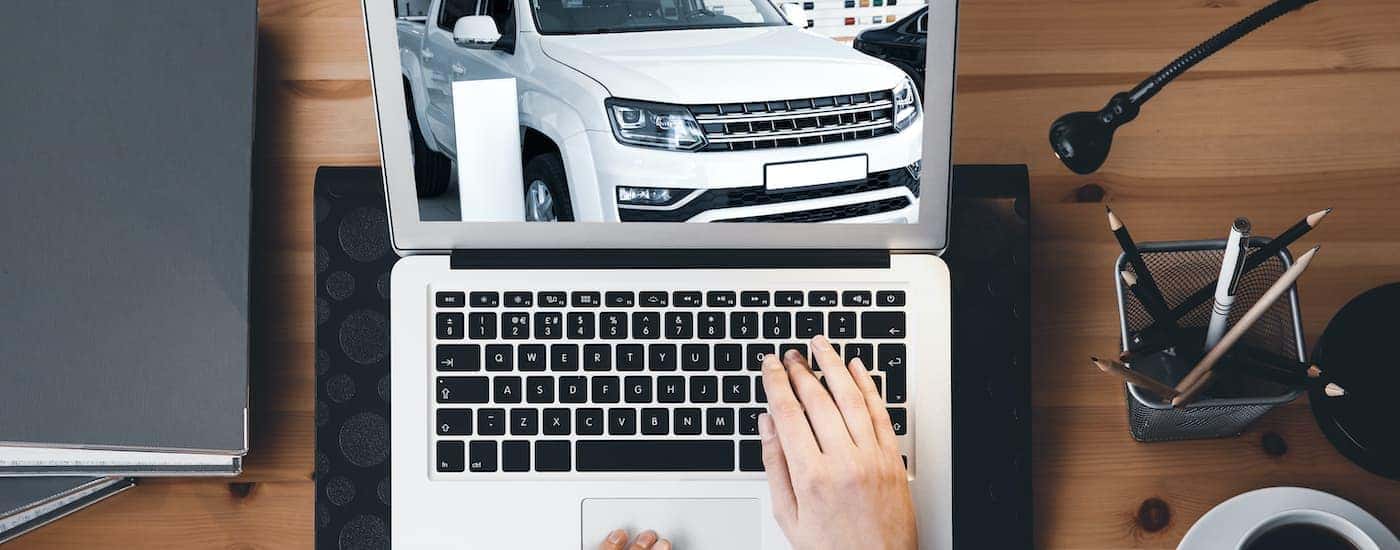 A hand is shown typing on a keyboard while searching for an Indianapolis online car dealer.