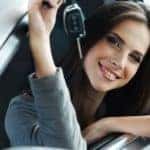 A woman is shown holding the key to her new car.