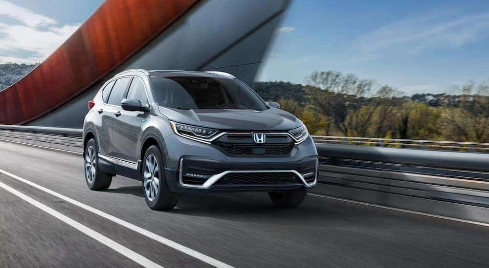 A grey 2020 Honda CR-V Touring is shown from the front driving on an open road.