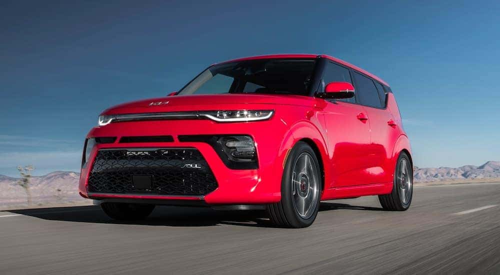 A red 2022 Kia Soul is shown driving on a road after visiting University City online car dealer.