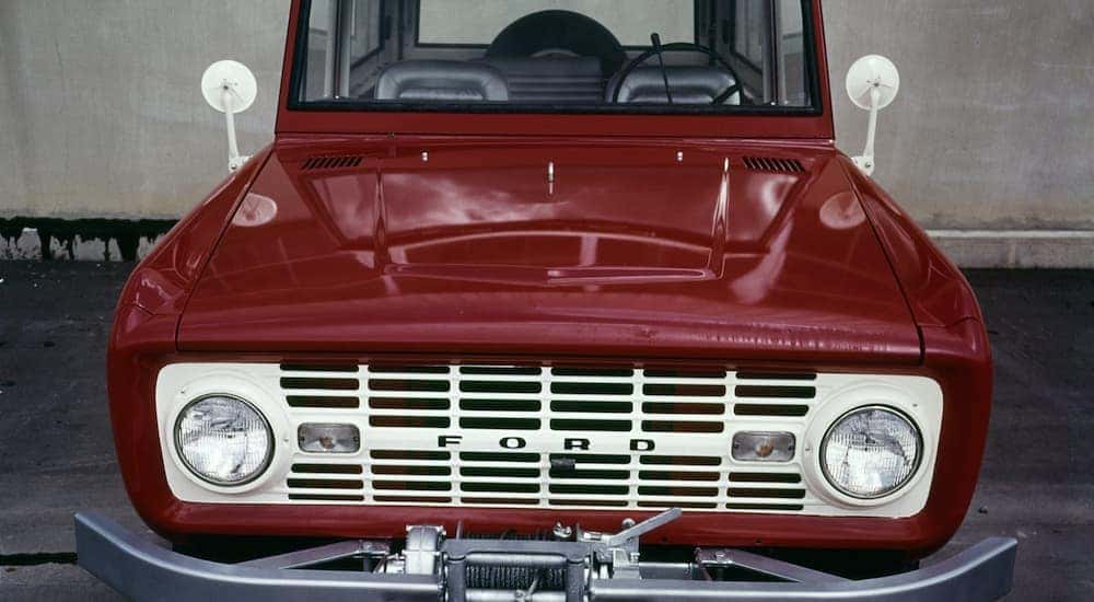 A red 1969 Ford Bronco is shown from the front parked inside of a gallery.