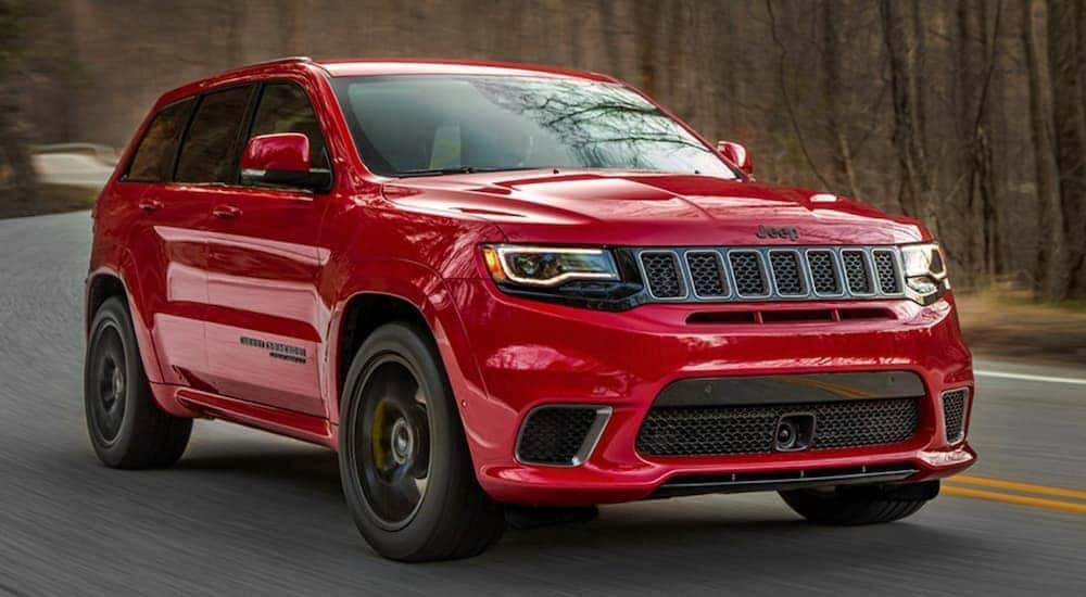 A red 2020 Jeep Grand Cherokee Trackhawk is shown from the front driving on an open road.