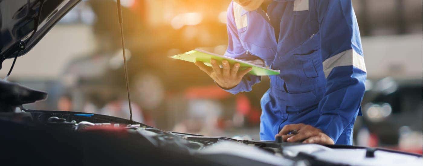 A mechanic is shown inspecting the engine of a used vehicle.