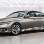 A tan 2020 Honda Accord Hybrid Touring is shown from the side parked in a modern gallery.