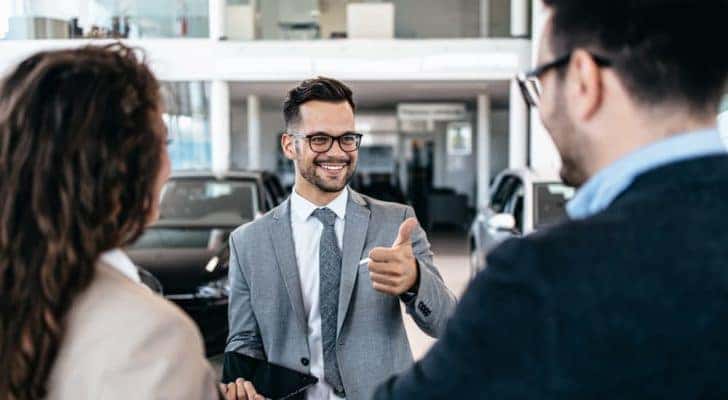 A salesman is shown giving a thumbs up at a Carmel online car dealership.