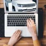 A person is shown reviewing a CarFax report when searching for a New Albany online car dealer.