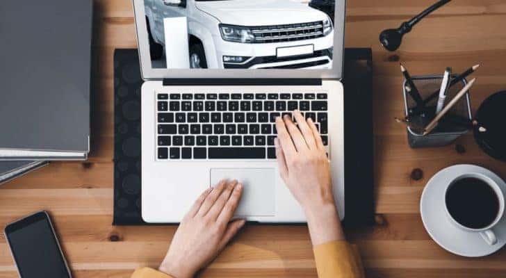 A person is shown on a laptop searching for cars at a Shively online car dealership.