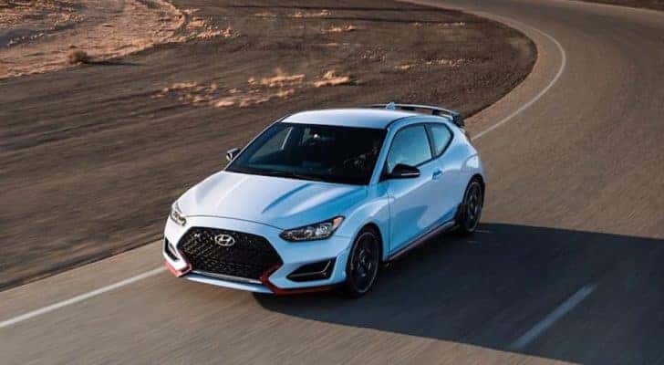 A 2022 Hyundai Veloster N is shown from the front at an angle while rounding a corner after the owner searched for 'Dallas online car sales'.