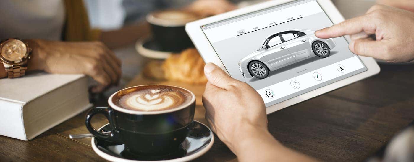 A person is shown looking at Phoenix online car sales on a tablet.