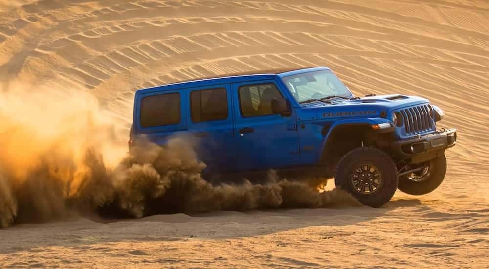A blue 2021 Jeep Wrangler Rubicon 392 is shown from the side at an angle while driving through the desert after the owner searched 'Phoenix online car sales'.