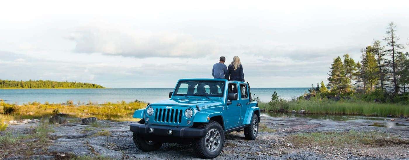 A popular vehicle for Houston online car sales, a blue 2021 Jeep Wrangler Unlimited Rubicon, is shown by a lake.