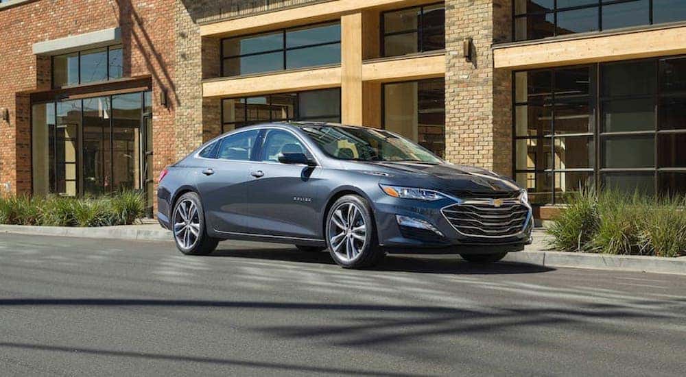 Side angled view of a grey 2019 Chevy Malibu parked on the side of a city street