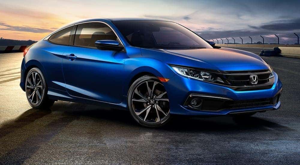 Side angled view of a blue 2020 Honda Civic Coupe Sport parked on a racetrack