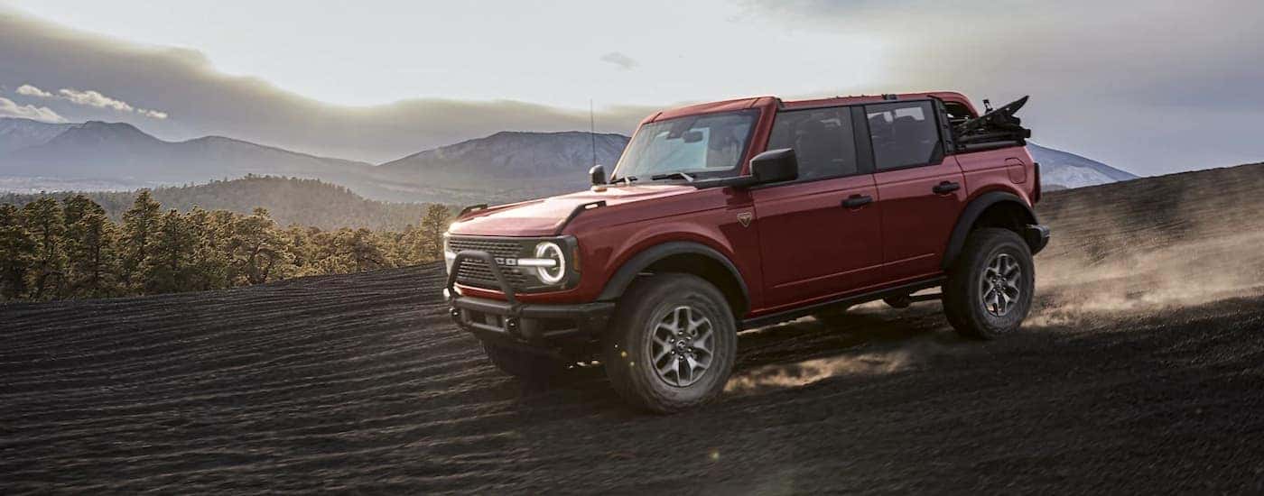 A red 2021 Ford Bronco Badlands is shown driving on a trail.