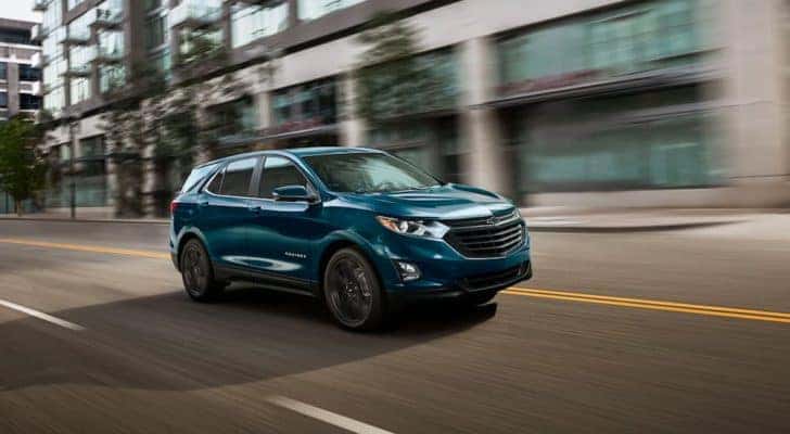 A teal 2021 Chevy Equinox is shown driving on a city street.