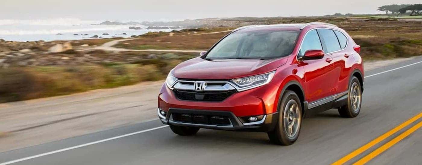 A red 2018 Honda CR-V is shown driving near a body of water.