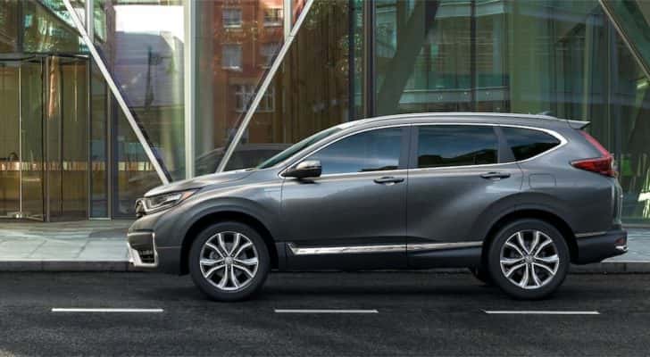 A grey 2022 Honda CR-V Hybrid is shown from the side driving on a city street.