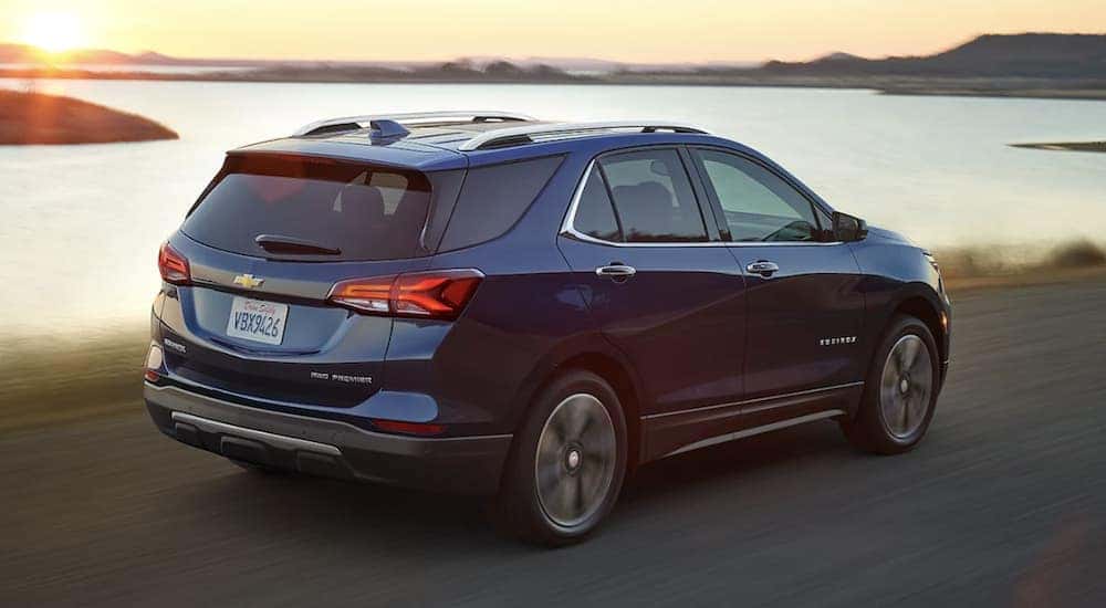 Side view of a blue 2022 Chevy Equinox driving past a body of water