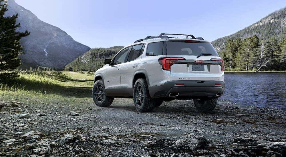 A white 2020 GMC Acadia AT4 is shown from the rear parked next to a river.
