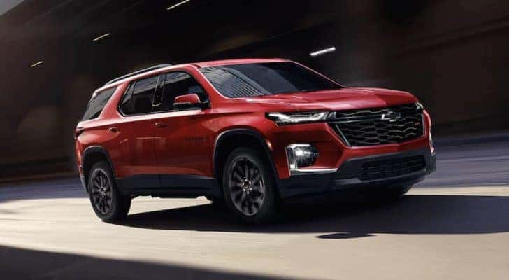 A red 2023 Chevy Traverse RS is shown driving on an open road.