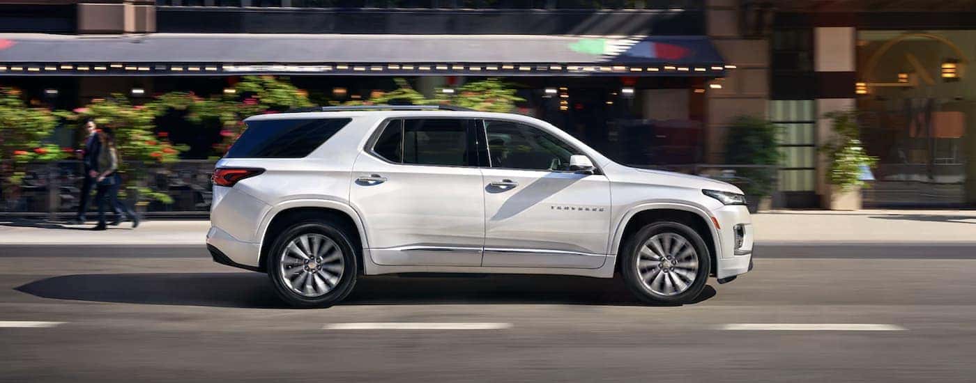 A white 2023 Chevy Traverse is shown from the side driving on an open road after searching online Chevy Traverse sales.