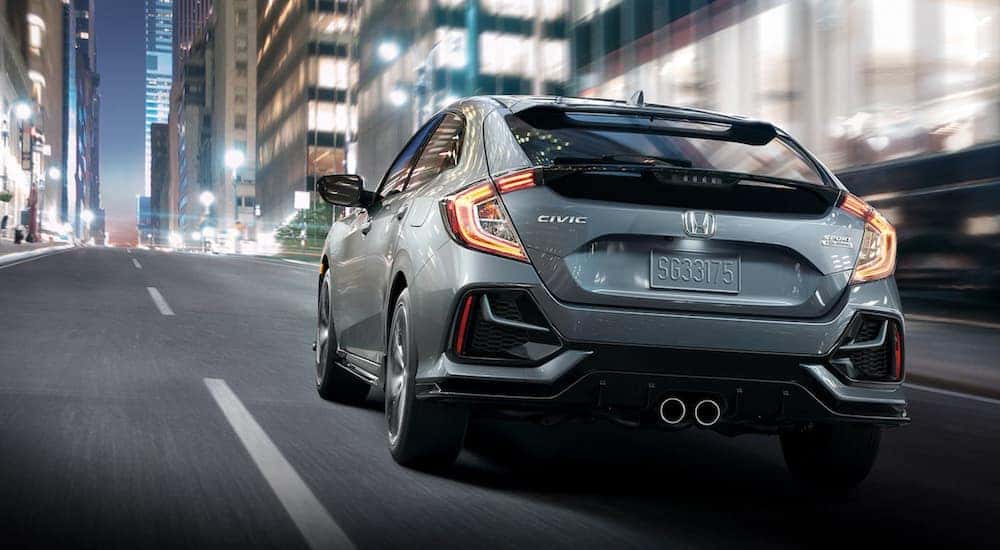 A grey 2020 Honda Civic Hatchback is shown from the rear on a city street.