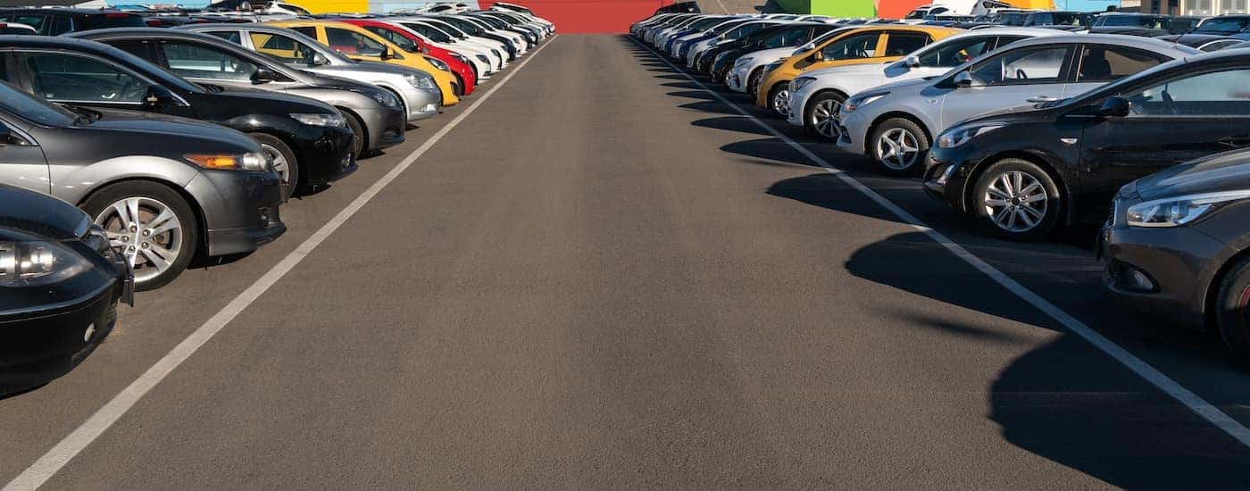 Two rows of vehicles are shown in a large parking lot.