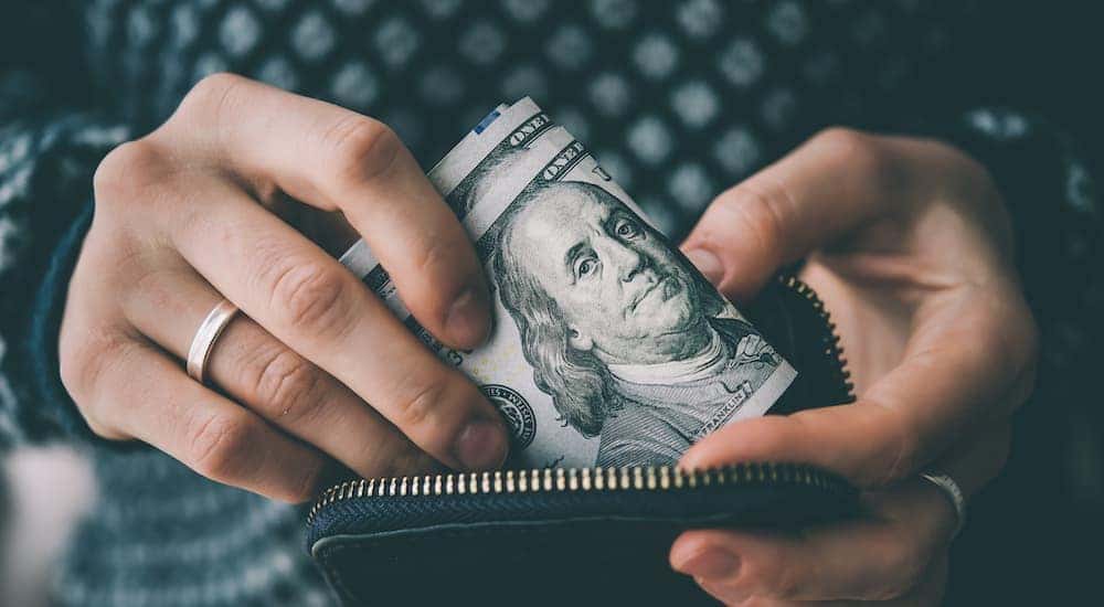 A person is shown putting cash in a purse.