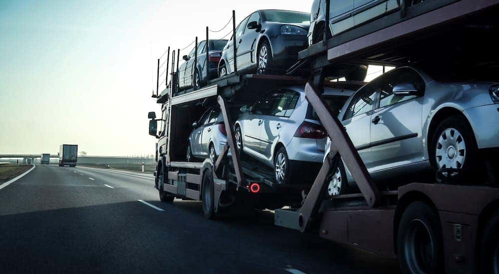 A car carrier trailer is shown delivering cars after leaving an online car dealer.