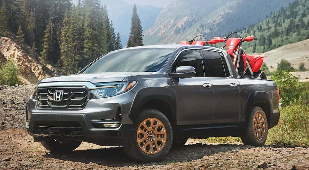 A grey 2021 Honda Ridgeline RTL-E is shown from the front at an angle while loaded with dirt-bikes.