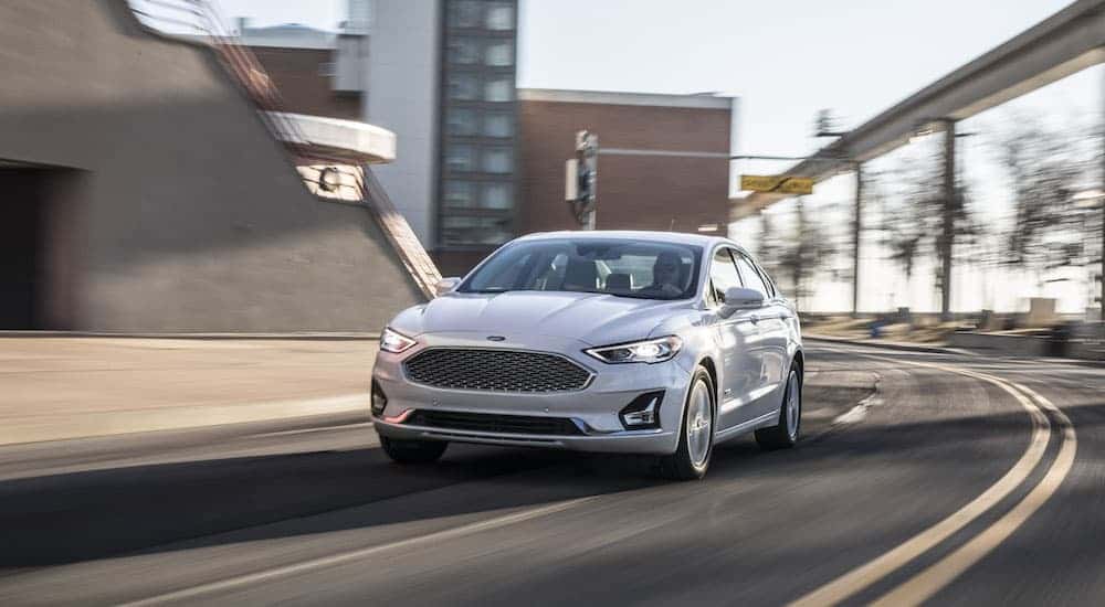 A white 2020 Ford Fusion is shown from the front at an angle while rounding a bend.