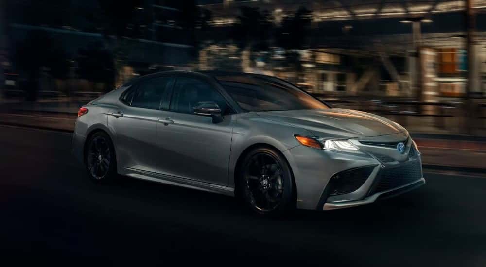 A silver 2022 Toyota Camry is shown driving on a city street at night after looking at Pittsburgh car sales.