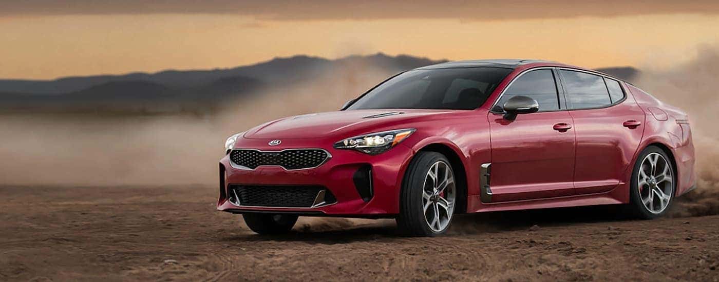 A red 2020 Kia Stinger is shown from the front while kicking up dust.