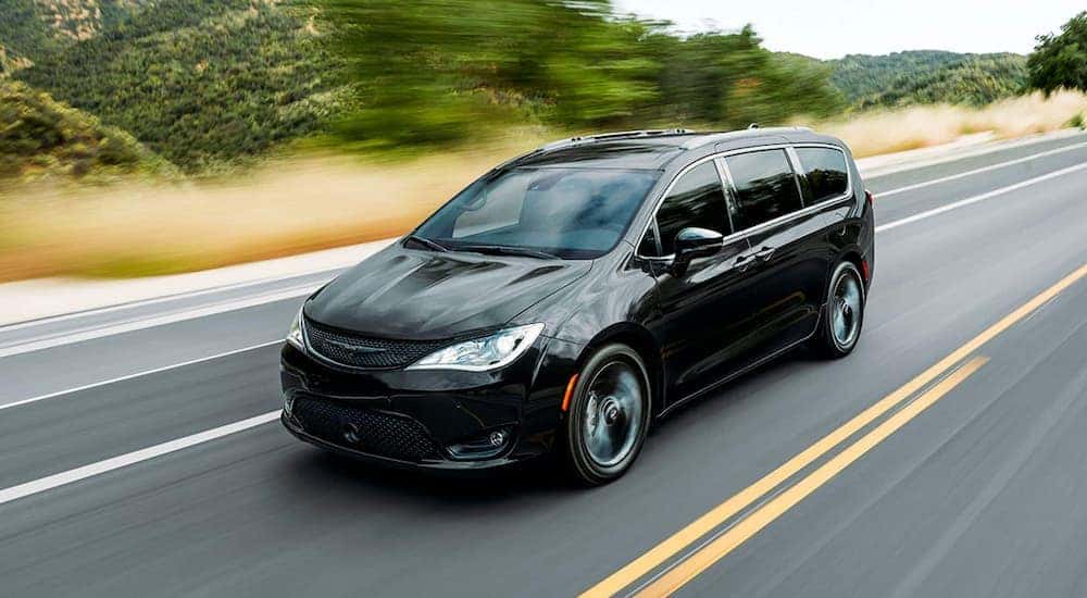 A black 2020 Chrysler Pacifica is shown driving on an open highway.