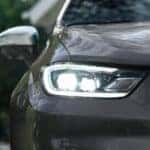 A close up of the headlight and grille on a grey 2022 Chrysler Pacifica is shown during a Birmingham car sale.