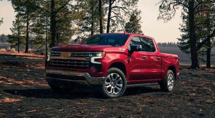 A popular vehicle for Charlotte car sales, a red 2023 Silverado 1500 Z71, is shown parked near trees.