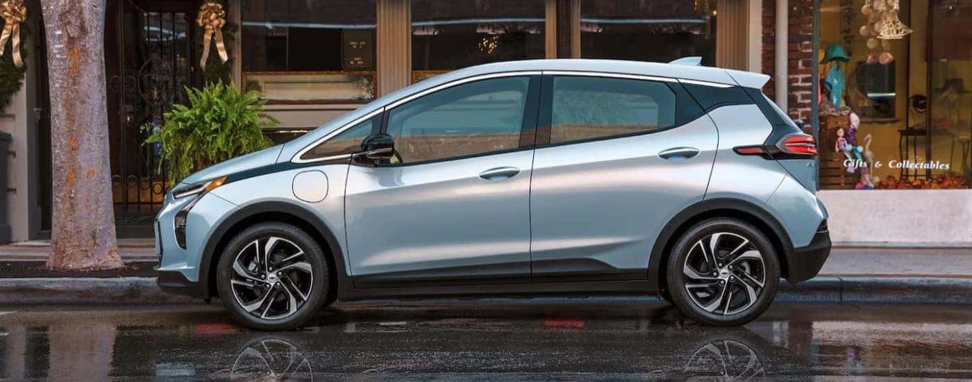 A light blue 2022 Chevy Bolt EV is shown from the side parked in front of a shop.