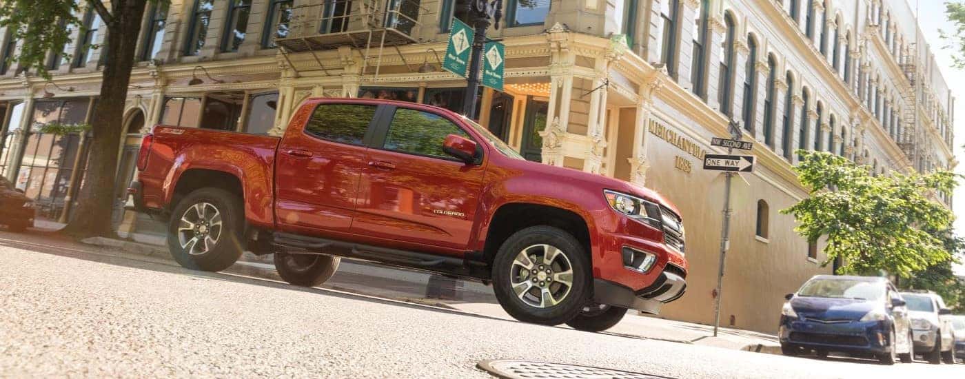 A red 2015 Chevy Colorado Z71 is shown form the side driving on a city street after looking at cars for sale in Washington, DC.