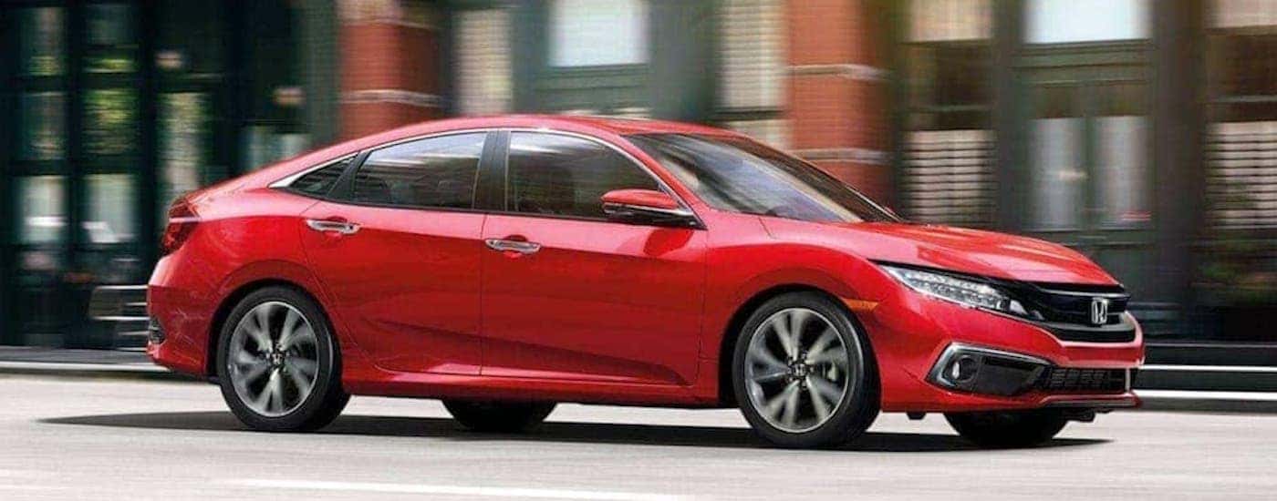 A red 2020 Honda Civic Sedan is shown from the side on a city street.