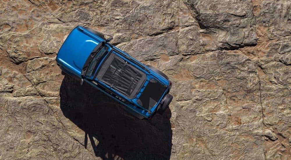 A blue 2021 Ford Bronco is shown from a high angle parked on rock.