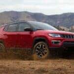 A red 2021 Jeep Compass TrailHawk is shown from the side while off-road.