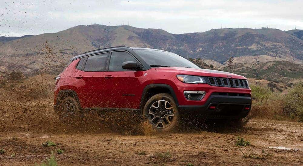 A red 2021 Jeep Compass TrailHawk is shown from the side while off-road.