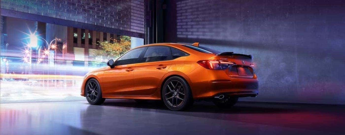 An orange 2022 Honda Civic Si is shown from the rear at an angle.