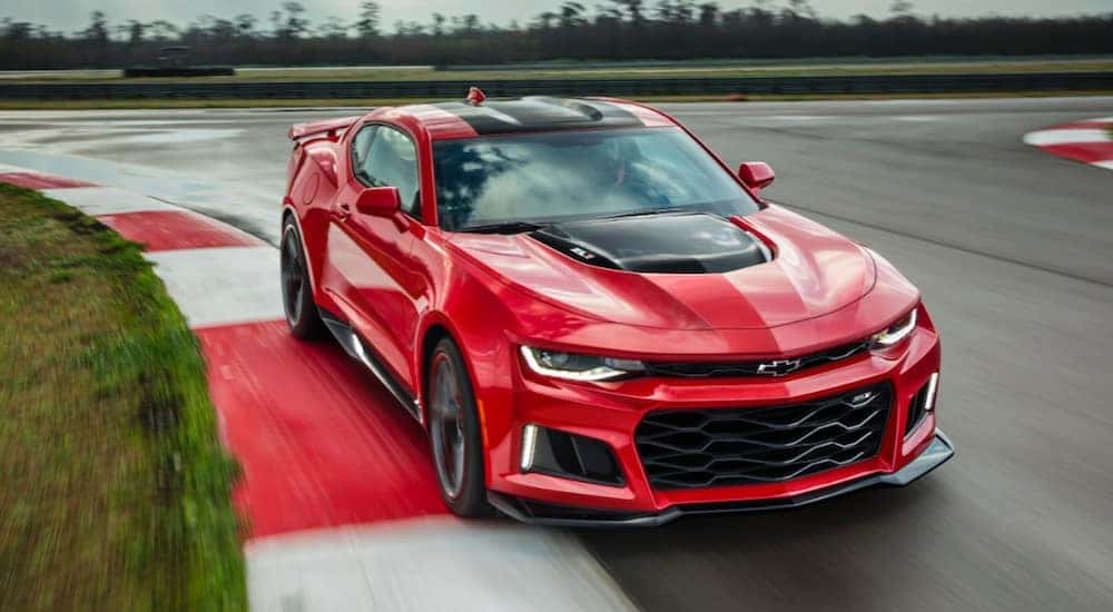 A red 2017 Chevy Camaro ZL1 is shown driving on a track after viewing cars for sale in Miami.