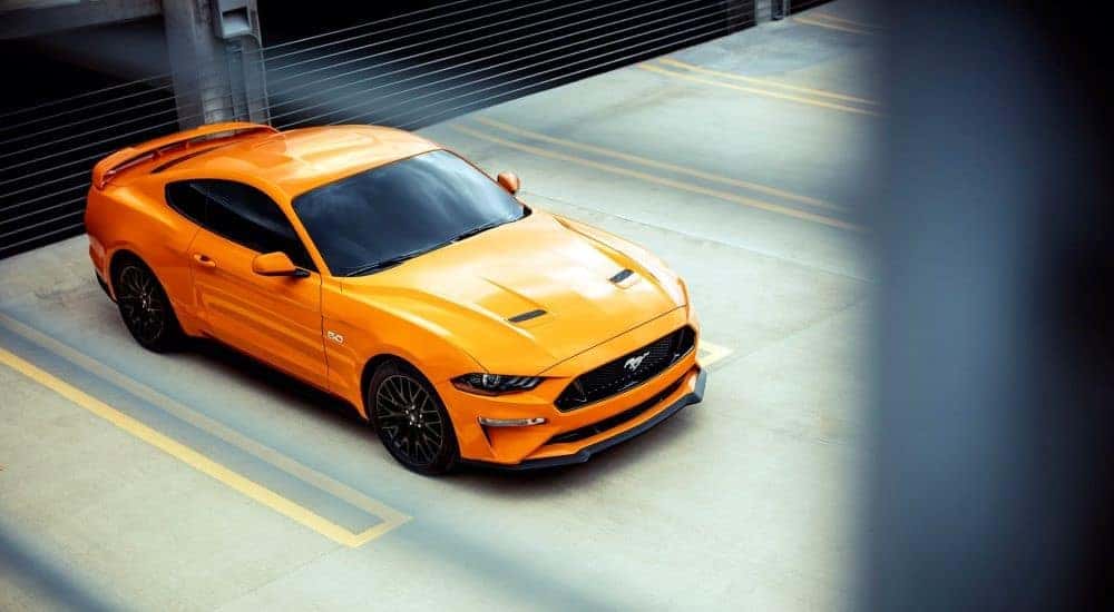 An orange 2018 Ford Mustang GT is shown parked in a parking garage.