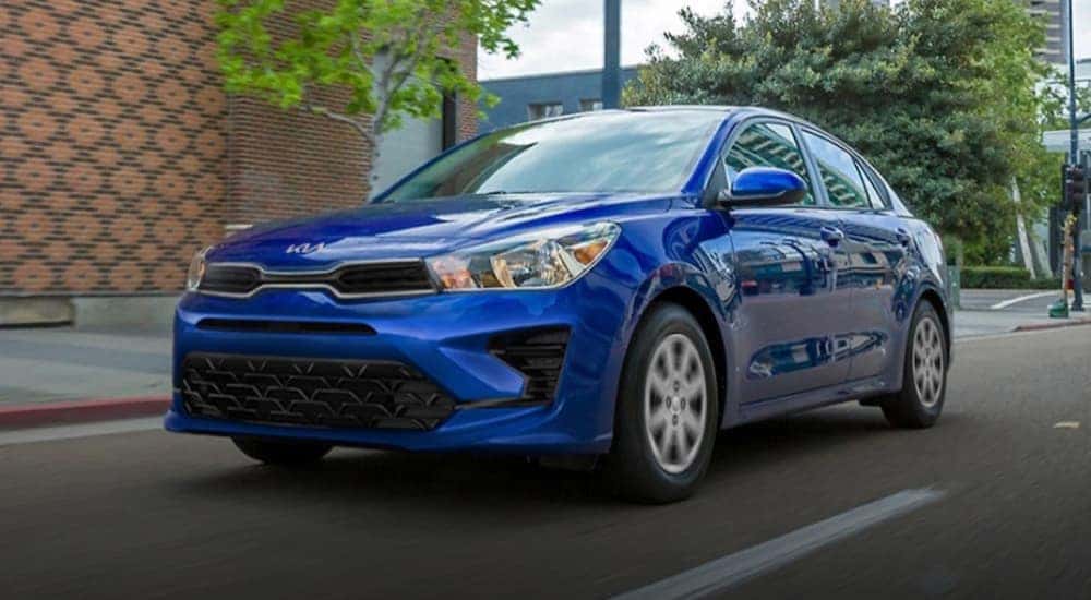A blue 2023 Kia Rio is shown driving on a city street after viewing cars for sale in Hartford.