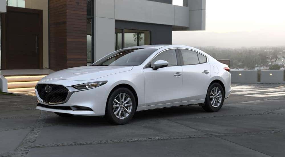 A white 2023 Mazda3 is shown parked near a house.