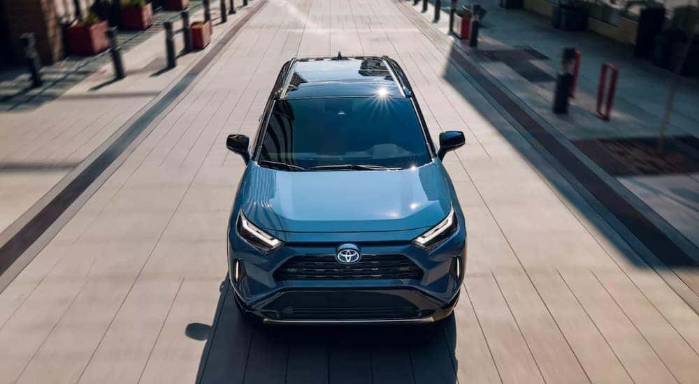 A blue 2023 Toyota RAV4 Hybrid XSE is shown driving on a city road.