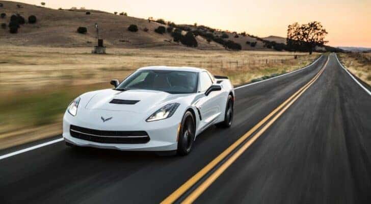 A white 2016 Chevy Corvette is shown from the front at an angle after leaving a dealer that has cars for sale in Miami.